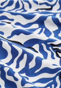 Modrá a bílá látka s plynulým, organickým vzorem, zdobená výraznými černými akcenty. Hladký povrch s lesklým finišem.