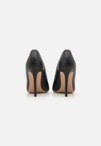 Sorte lærhøye hæler med spiss tådesign og en elegant silhuett. Glatt tekstur og slanke stiletthæler.