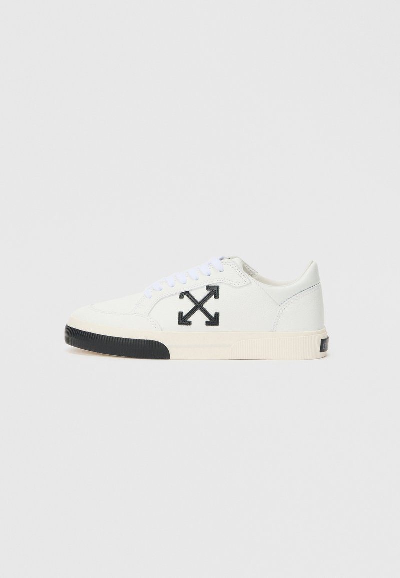 Sneaker alb din piele, cu un logo negru având săgeți, vârf rotund, șireturi albe și o talpă din cauciuc negru.