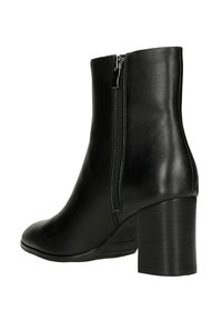 Černá kožená kotníková bota s kulatou špičkou, bočním zipem a masivním podpatkem. Vyznačuje se hladkým povrchem a elegantním designem.