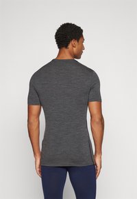 T-shirt ajustado de manga curta em cinza escuro, feito de um tecido texturizado; apresenta um corte redondo e detalhes de costura discretos.