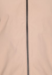 Giacca beige chiaro con cerniera frontale con ferramenta nera, tessuto liscio e design minimalista senza decorazioni aggiuntive.