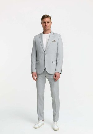 Light grey suit with notch lapels, single-button closure, and side pockets. Paired with a white t-shirt and white sneakers.