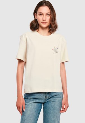 Cream-colored T-shirt made of soft cotton, featuring a small floral vase design on the left chest. Short sleeves and relaxed fit.