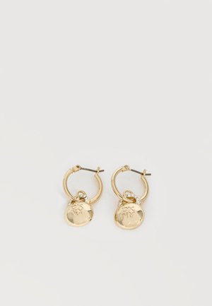 Pendientes de aro dorados con colgantes redondos del logo de DKNY y pequeños cristales incrustados sobre un fondo blanco.