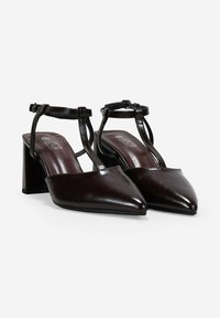 Tacones slingback de piel marrón con punta afilada, tacón cuadrado y correa en el tobillo, con un acabado brillante y un diseño elegante.