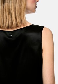 Schwarzes satiniertes ärmelloses Oberteil mit rundem Ausschnitt und Knopfdetail am Rücken, mit glatter und glänzender Textur.