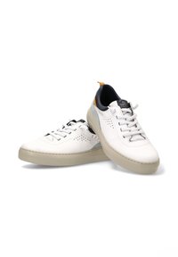 Zapatillas de cuero blancas con un perfil bajo, superficie texturizada y suelas de goma gris claro. Los detalles incluyen un talón azul marino y una etiqueta naranja.