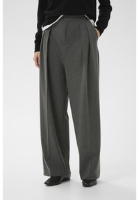 Hallid, voltidega laiade säärega püksid tekstuurse kangaga. Omavad küljetaskuid ja istuvad vormilt hästi. Kandmiseks sobitatud mustade jalanõudega.