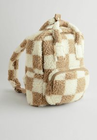 Sac à dos à carreaux avec texture duveteuse en beige et crème, avec une poche zippée à l'avant et des bretelles réglables pour le portage.