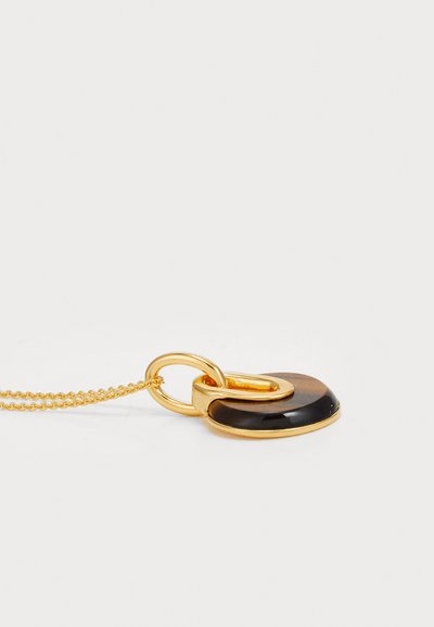 Collier doré avec un pendentif circulaire en pierre noire et un anneau doré lié, texture lisse et finition polie.