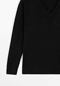 Zwarte v-hals trui met lange mouwen. Gebreide structuur en geribbelde manchetten en zoom. Eenvoudig, minimalistisch ontwerp zonder patronen of accenten.