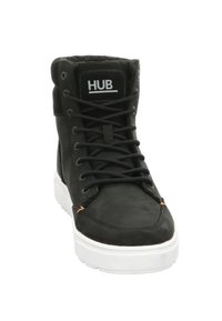 Zwarte hoge sneaker met een glad leren buitenkant, witte rubberen zool, zwarte veters en oranje accentstiksels. Voorzien van het HUB-logo.