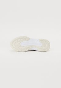 Weißer Sportschuh mit einer strukturierten Gummisohle, der ein glattes Oberdesign und helle Cremeakzente an der Ferse und den Sohlenkanten aufweist.