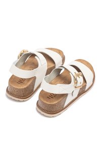 Sandalias de plataforma de cuero blanco con acabado texturizado, correa ajustable y herrajes en tono dorado. Plantilla de corcho y suela de goma.