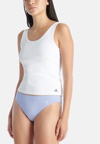 Top in cotone bianco a coste con spalline larghe abbinato a slip bikini viola chiaro caratterizzato da tre righe diagonali. Entrambi gli articoli hanno una texture liscia.