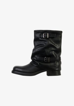 Zwarte leren enkellaars met een slouchy ontwerp, twee metalen gespen op riempjes, een stevige hak en een afgeronde neus. Gladde textuur.