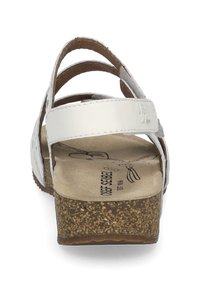 White leather sandal with a cork wedge sole, multiple narrow straps across the top, and a textured beige footbed.