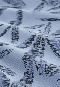 Tissu présentant un fond bleu clair avec des motifs de feuilles abstraits en noir et bleu foncé. Le tissu a un tissage texturé avec des coutures visibles.