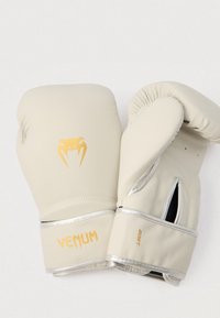 Μπεζ γάντια πυγμαχίας με χρυσές λεπτομέρειες, με λογότυπο κόμπρα, ασημένιες επενδύσεις και ανοικτό σχεδιασμό αντίχειρα για αναπνοή και άνεση.