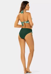 Zielony bikini o wysokim stanie z bocznymi związkami oraz halter top w tropikalny wzór z zielonymi i białymi liśćmi. Gładka tekstura materiału.