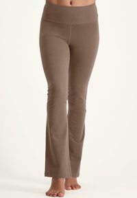 Leggings marron évasés en tissu doux et extensible. Dotés d'une large taille et d'une texture lisse, offrant une silhouette ajustée.