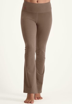 Braune, ausgestellte Leggings aus weichem, elastischem Material. Sie verfügen über einen breiten Bund und eine glatte Textur, die eine figurschmeichelnde Silhouette bietet.