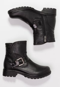 Bottines noires en cuir synthétique. Elles comportent une fermeture éclair sur le côté, une sangle avec une boucle métallique, une semelle texturée et des coutures décoratives.