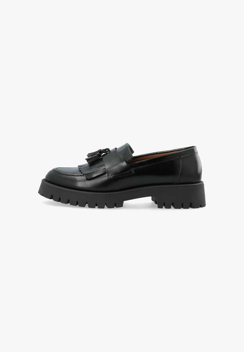 Mocassin en cuir noir avec une semelle épaisse à crampons, des glands décoratifs et des franges sur le dessus, vu de profil sur fond blanc.