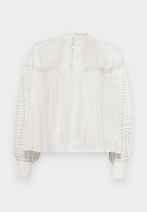 Blusa bianca con collo alto, chiusura con bottoni, anteriore testurizzato e maniche puff, caratterizzate da tessuto plissettato e polsini elastici.