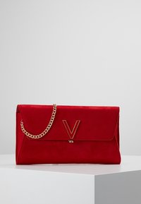 Punainen mokkanahkainen kirjekuorilaukku, jossa on kultainen ketjuhihna ja V-muotoisella metallikoristeella varustettu etutasku sekä sileä pinta.