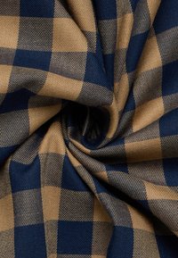 Blue and tan checkered fabric folded with a central twist, highlighting the woven texture and pattern detail.