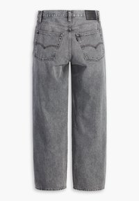 Vue arrière d'un jean en denim gris avec deux poches arrière, des passants pour ceinture et un patch en cuir de la marque sur la ceinture.