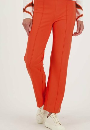 Oranje wijde broek met verticale naden, gemaakt van gladde stof. Gecombineerd met crèmekleurige sneakers.