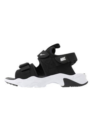 Sort Nike sportssandal med hvid tyk sål, justerbare remme, Nike-logo på siden og den øverste rem, sidevisning på hvid baggrund.