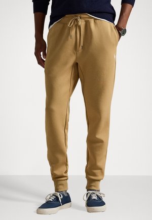 Beige Sweatpants mit einer lockeren Passform, featuring Zugband-Bündchen, Seitentaschen und einem kleinen Logo auf dem Oberschenkel. Weiches, strukturierte Material.