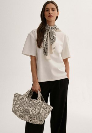 Biała bluzka z krótkim rękawem, wzorzysty czarno-kremowy szalik, czarne szerokie spodnie oraz torba w nadruk paisley z czarnymi uchwytami.