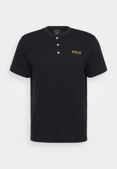 Camisa polo preta de manga curta com textura canelada, pala com três botões e logo amarelo "POLO" no peito.