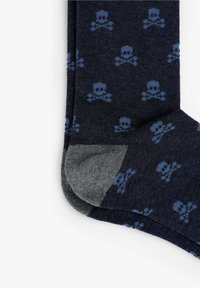 Calcetines en color navy con un patrón de calavera y huesos cruzados en azul claro; material de punto texturizado con la puntera y el talón reforzados en gris.
