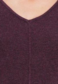 Pull en tricot bordeaux, avec un col en V, un tissu texturé et un motif à côtes léger sur l'ensemble. Apparence douce et confortable.