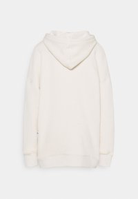 Felpa color crema realizzata in un tessuto morbido. Presenta una vestibilità rilassata, maniche lunghe e un cappuccio a doppio strato. Design semplice, senza motivi o dettagli.