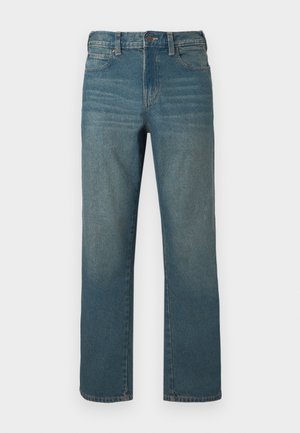 Jean en denim bleu moyen, coupe droite, avec une fermeture à boutons, cinq poches, et un léger délavage à l'avant.