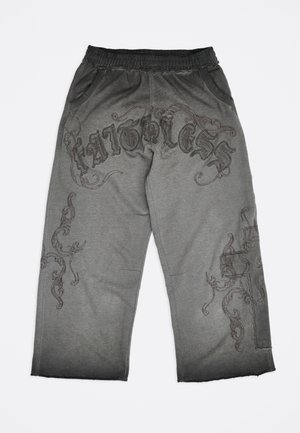 Sive široke hlače z črnim elastičnim pasom, dekorativnim temnim vzorcem v obliki vijug in napisom "FATIGUES" čez sprednji zgornji del stegnen.
