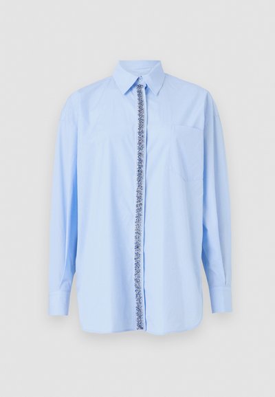 Light blue long-sleeve shirt with a pointed collar, front closure featuring a floral pattern, and a left chest pocket. Smooth fabric texture.