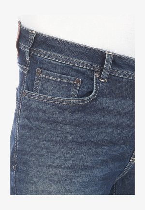 Jeans in denim blu scuro, caratterizzati da un classico design a cinque tasche, dettagli di cucitura e una texture liscia con una patch in pelle sulla vita.