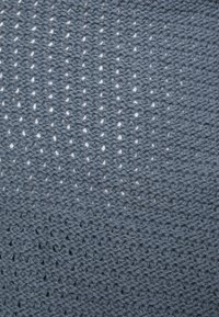 Närbild av blått stickat tyg som visar en strukturerad, öppen vävstruktur med små diamantformade hål.