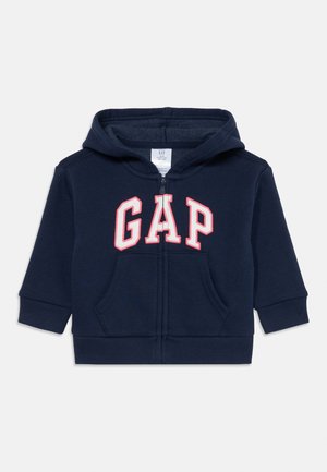 Felpa con cappuccio per bambino di colore blu navy, con zip frontale, tasca a marsupio e logo "GAP" in lettere bianche contornate di rosso sulla parte frontale.