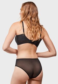 Conjunto de lencería negra que presenta un sujetador liso con detalles de encaje y unas braguitas altas sheer a juego, mostradas desde atrás.