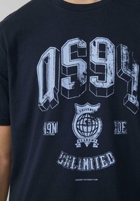 Marineblauwe katoenen t-shirt met gedurfde witte graphics, waaronder 'QS94' en een wereldbol-logo, met een ronde hals en korte mouwen.