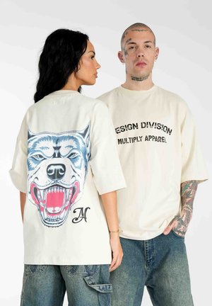 Cremefarvet oversized t-shirt med grafik af en snerrende ulv på ryggen og fed tekst på forsiden. Korte ærmer og afslappet pasform.